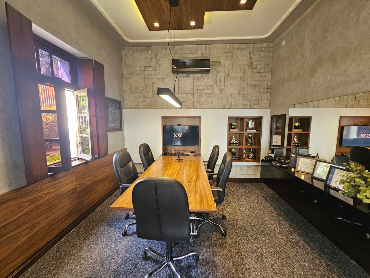Sala de reuniões da KW Advocacia com mesa de madeira e painel com o logotipo do escritório
